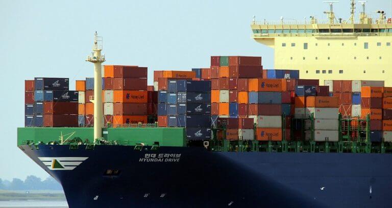 A massive cargo ship loaded with colorful shipping containers navigates the water, showcasing the vibrant nature of maritime commerce.
