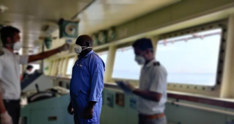 Crew members aboard a ship, engaged in navigation and operations, while diligently following health and safety protocols by wearing masks.