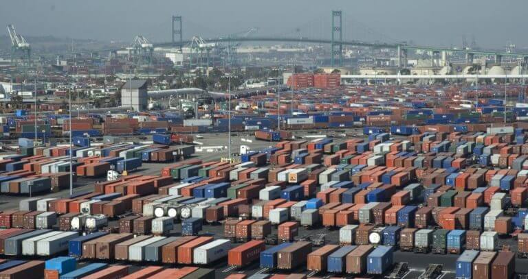 A sprawling cargo container yard at a busy port, showcasing the scale of global shipping and trade.